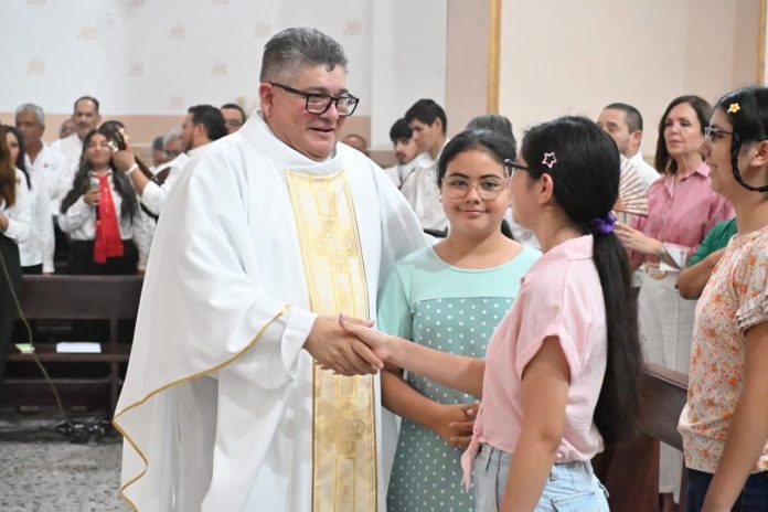 Padre José López Sandoval saludando a jóvenes en la parroquia Sagrado Corazón de Jesús en Frontera.